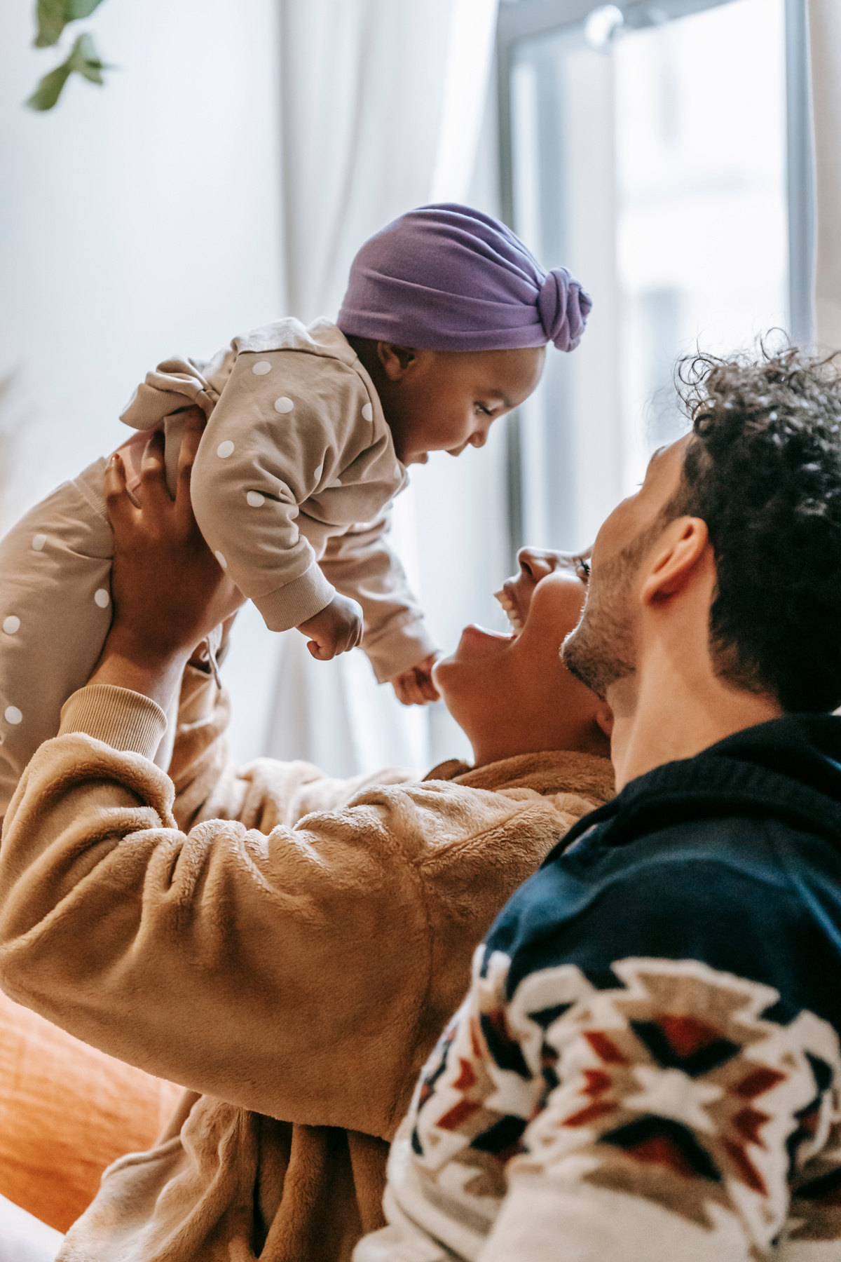 Loving multiethnic happy parents playing with baby